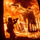 Firefighter Jose Corona sprays water as flames consume from the Camp Fire consume a home in Magalia, Calif., on Friday, Nov. 9, 2018.